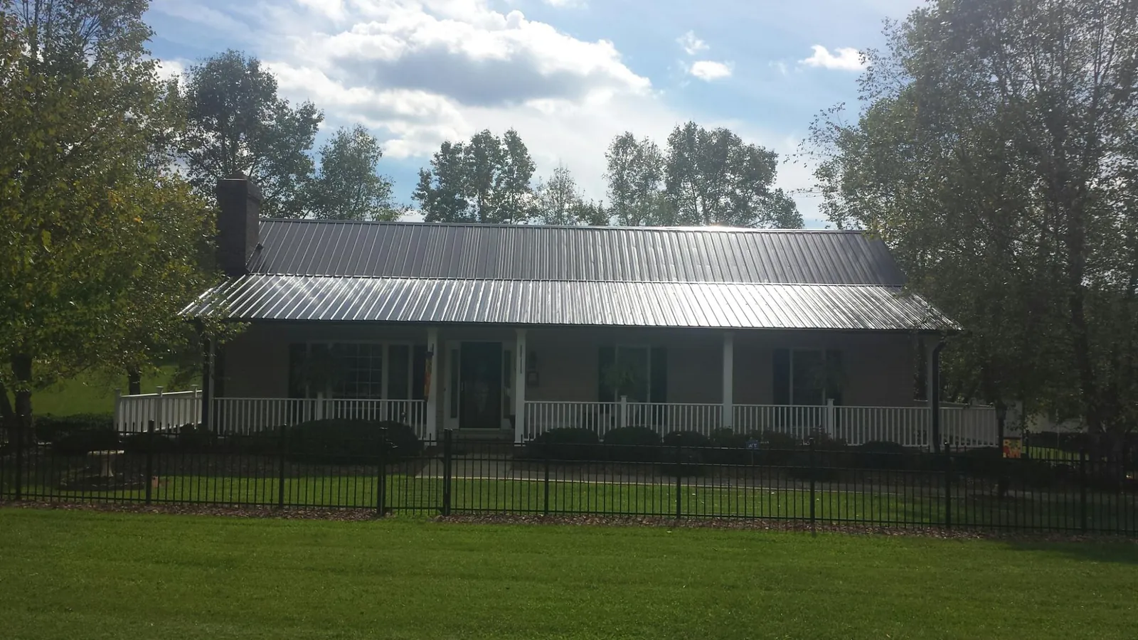 Gray metal roof on a brick ranch with a full width front porch — Gutter Guard Installation work by our crew in Saint Albans