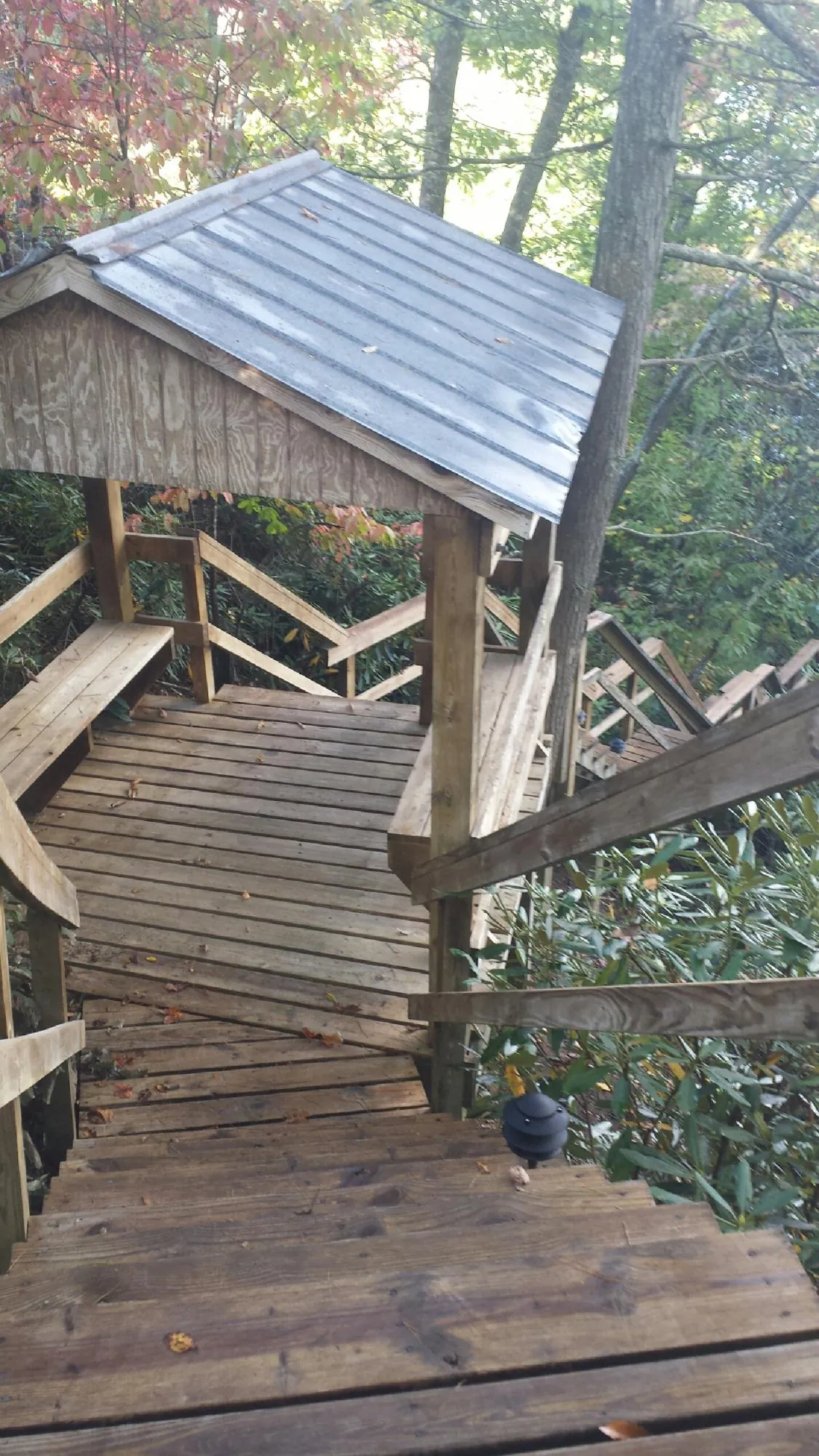 Metal roofed shelter over wooden steps on a wooded walkway — Skylight Repair & Installation work by our crew in Saint Albans