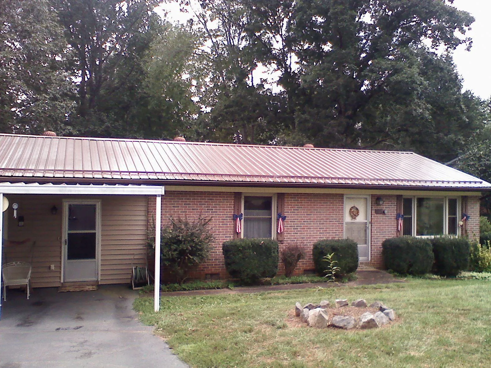 Bronze metal roof and carport on a brick ranch home — Roof Repair work by our crew in Saint Albans